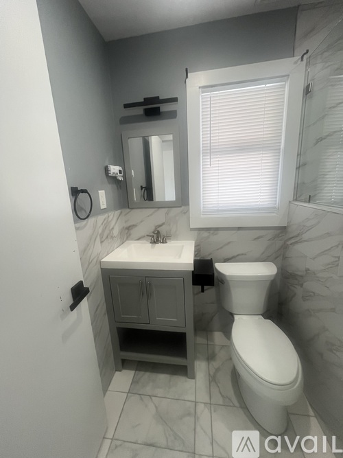 A bathroom with a toilet, sink, and mirror.
