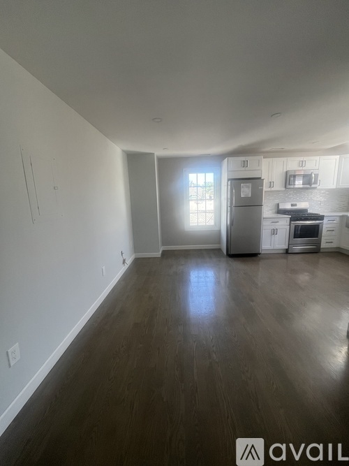A spacious living room with a kitchen in the background.