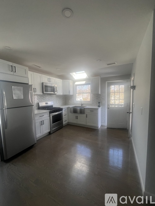 A kitchen with white cabinets and a stainless steel refrigerator.