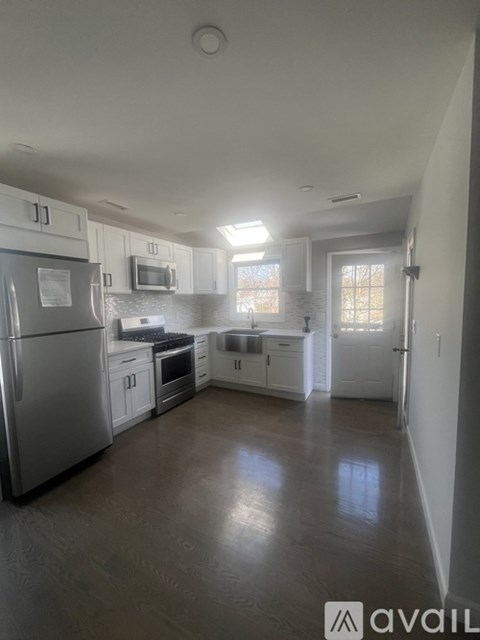 A kitchen with white cabinets and a stainless steel refrigerator.