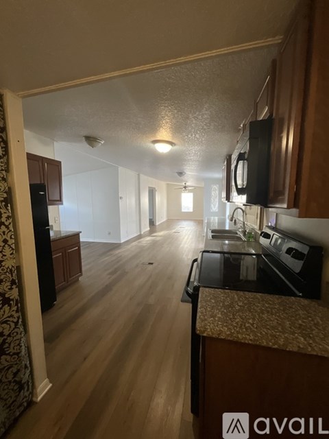 A kitchen with wooden floors and black appliances.