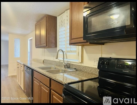 A kitchen with a black stove top oven and a black microwave above the sink.