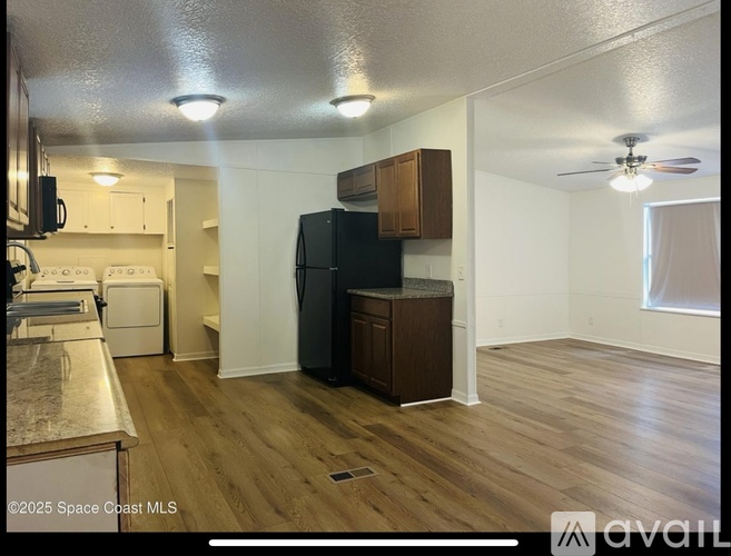 A kitchen with a refrigerator, microwave, and oven.