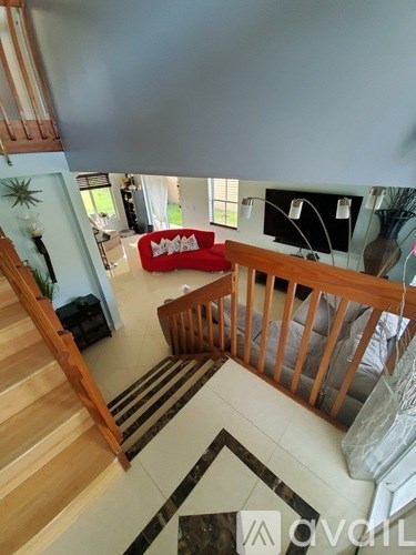 A living room with a red couch and a wooden staircase.
