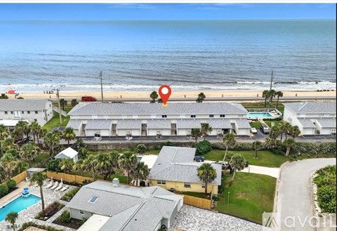 A beachfront property with a swimming pool and a red location marker.
