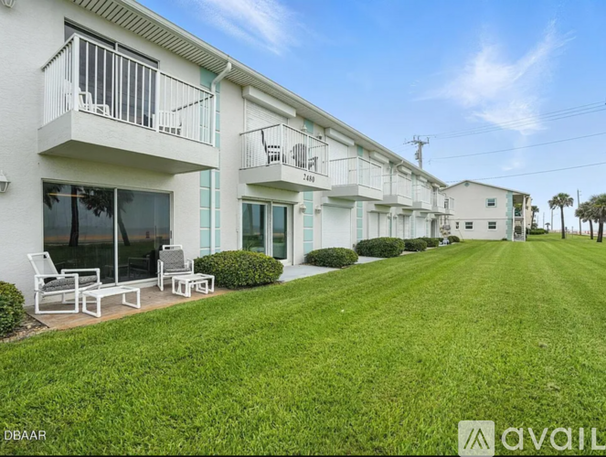 A row of white apartment buildings with balconies and green lawns.