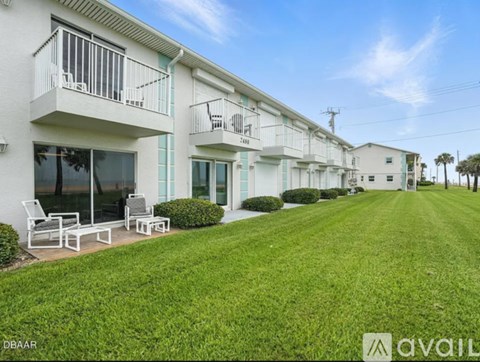 A row of white apartment buildings with balconies and green lawns.