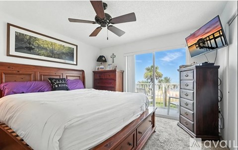 A bedroom with a large bed and a ceiling fan.