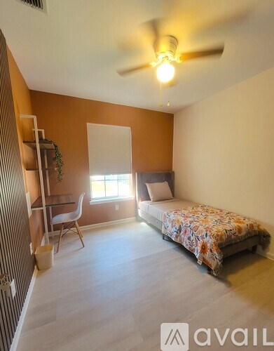 A bedroom with a bed, desk, and chair.