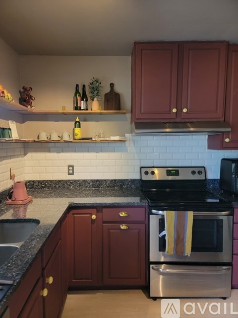 A kitchen with dark wood cabinets and a black stove top oven.