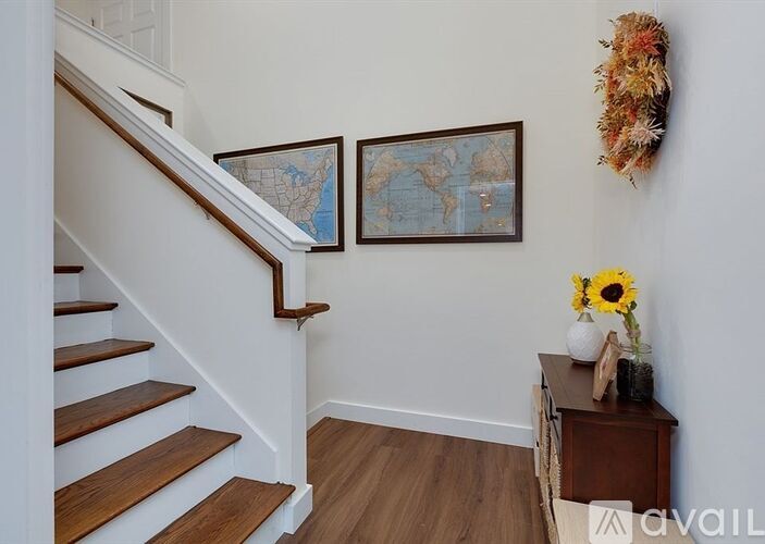 A staircase with a wooden banister and steps, a world map on the wall, and a sunflower on a side table.