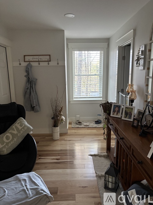 A living room with a black couch and a wooden floor.