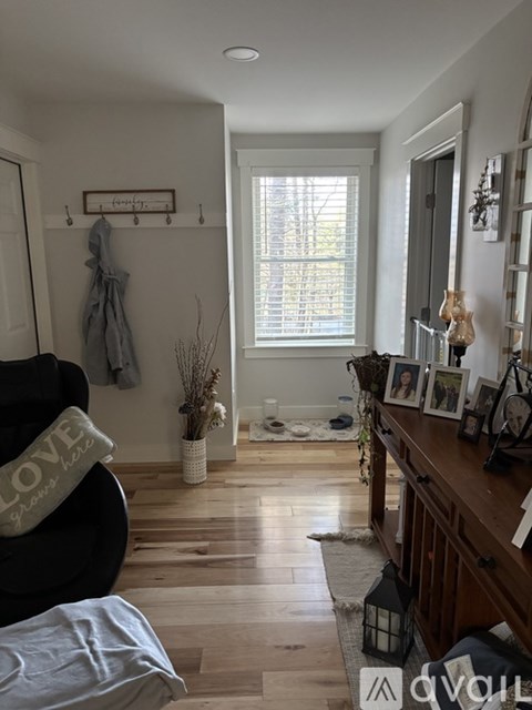 A living room with a black couch and a wooden floor.