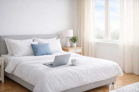 A laptop is on a bed with a cup of coffee and a small potted plant.