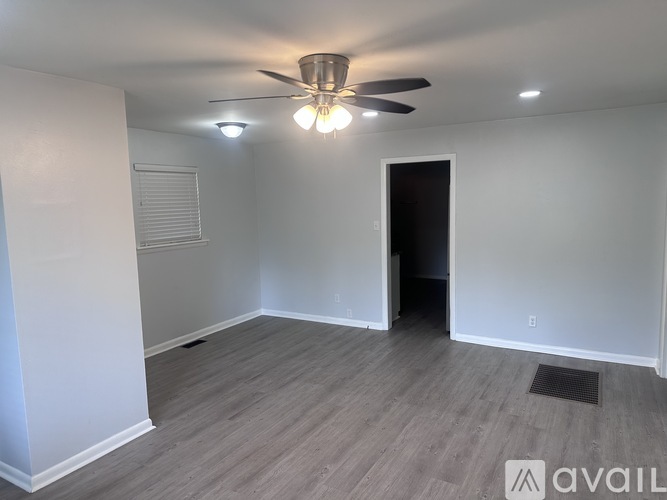 A room with a ceiling fan and light fixture, and a doorway leading to another room.