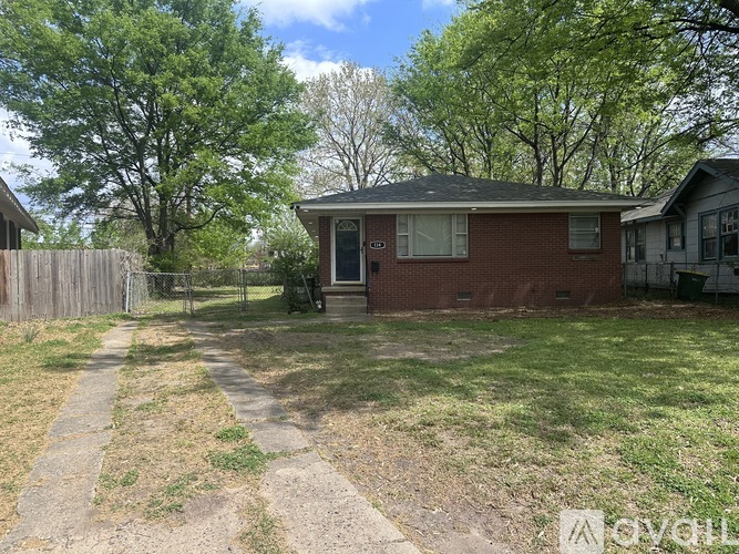 A small red brick house with a white door and a small porch.
