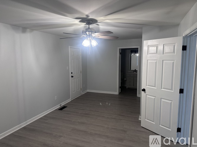 A room with a ceiling fan and light, and a door on the right.
