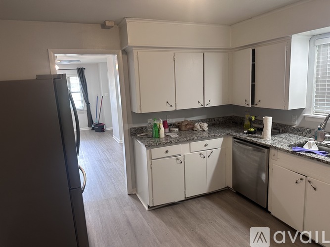 A kitchen with white cabinets and a black refrigerator.