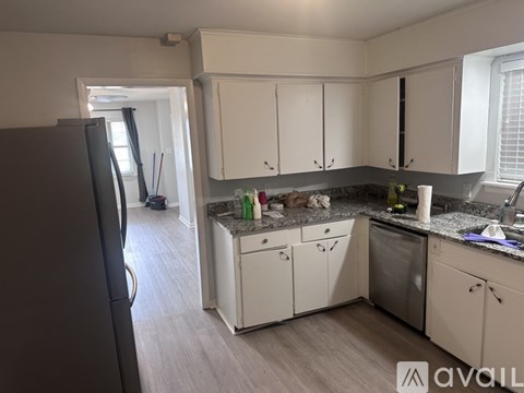 A kitchen with white cabinets and a black refrigerator.