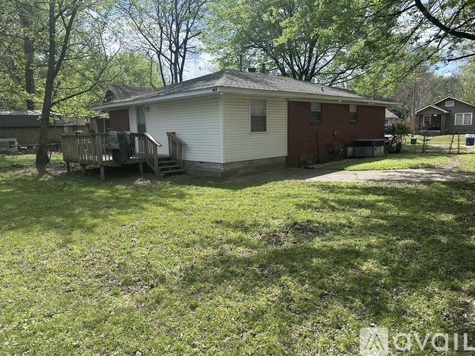 A house with a red brick wall and a white siding is surrounded by a grassy area.