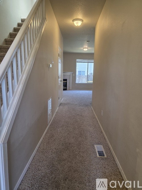 A long hallway with a staircase on the left and a door on the right.