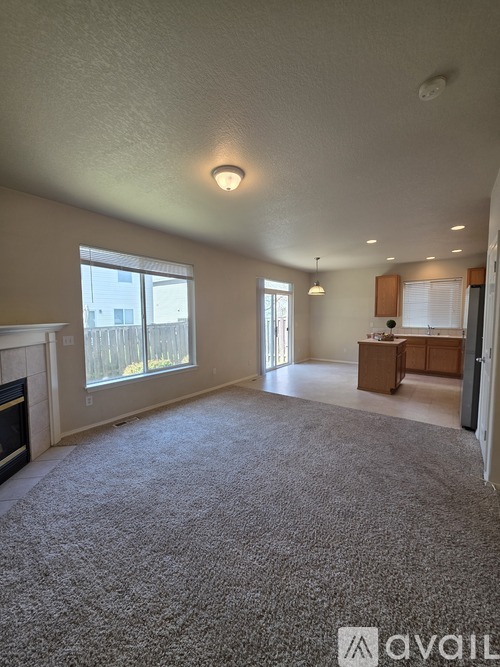 A living room with a carpeted floor and a fireplace.