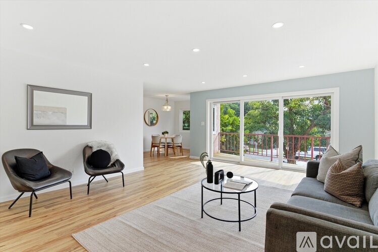A living room with a grey couch, two chairs, a coffee table, and a painting on the wall.