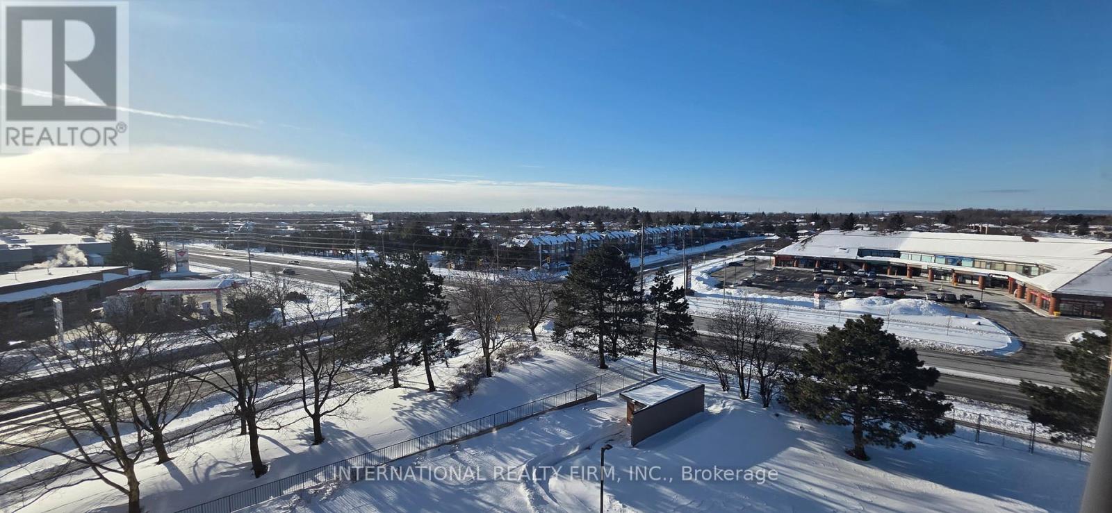 A view of a snowy landscape with a building and trees in the foreground.