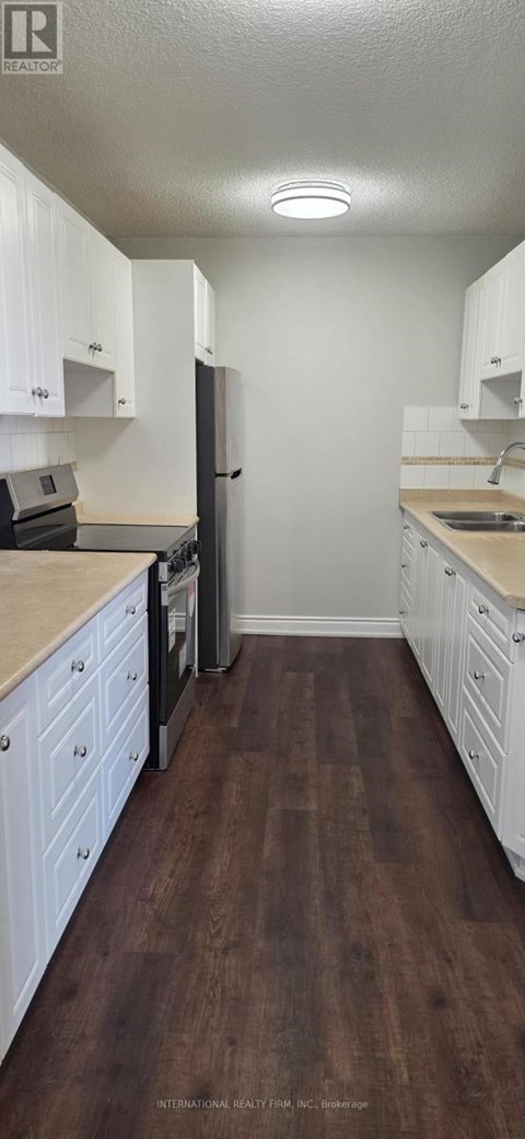 A kitchen with white cabinets and a wooden floor.