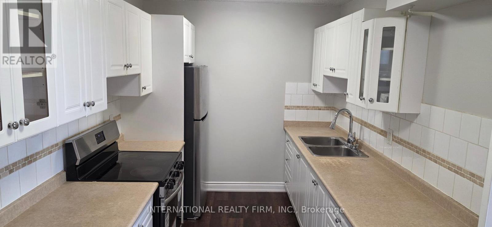 A kitchen with white cabinets and a black refrigerator.