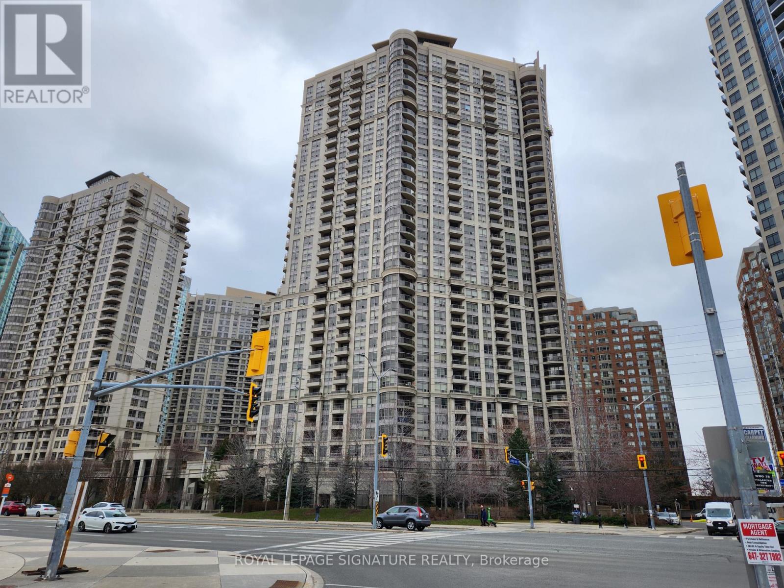 A tall building with many windows is in the background of a busy street.