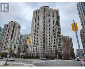 A tall building with many windows is in the background of a busy street.
