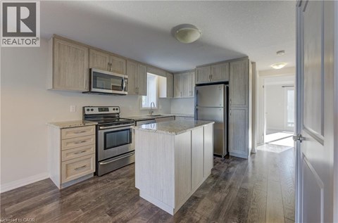 A kitchen with wooden cabinets and a microwave above the stove.