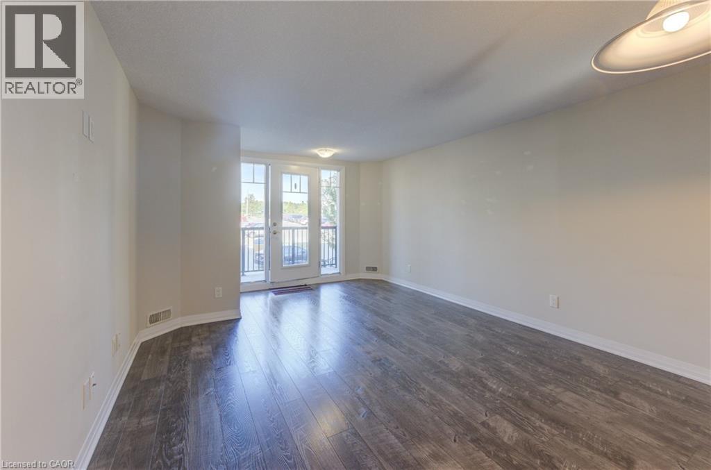 A spacious room with wooden flooring and a sliding glass door.