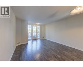 A spacious room with wooden flooring and a sliding glass door.