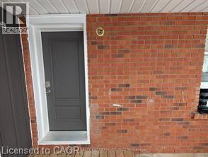 A grey door is on the left and a brick wall is on the right.