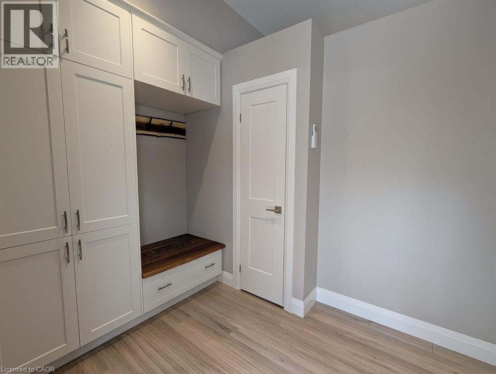 A white closet with a door open and a bench underneath.