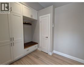 A white closet with a door open and a bench underneath.
