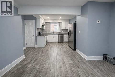 A kitchen with a white door and a fridge.