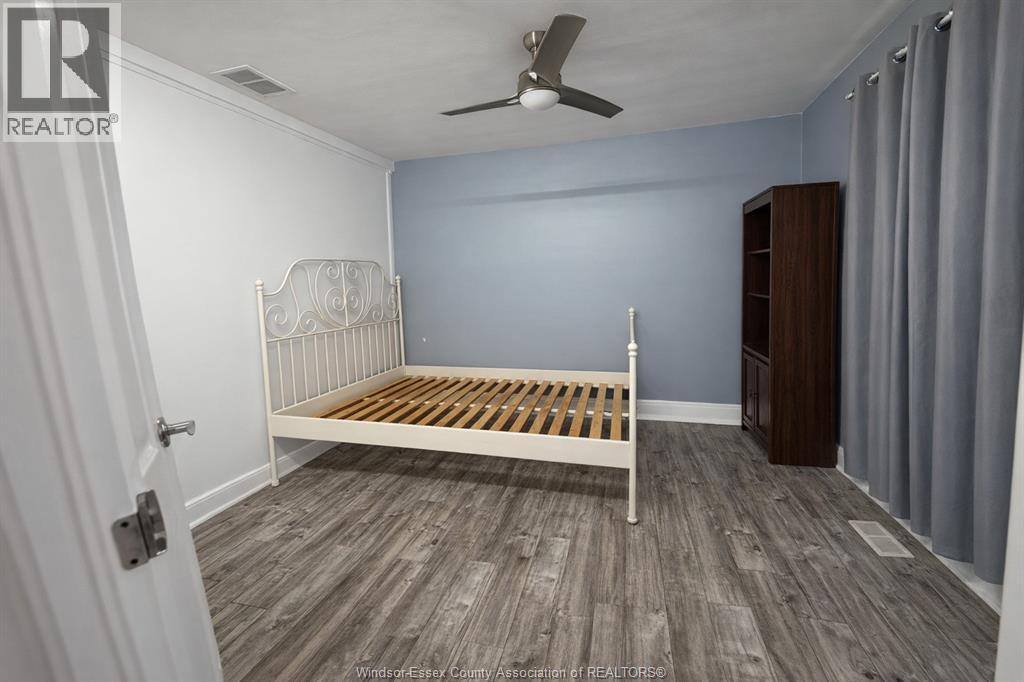 A bedroom with a bed, dresser, and ceiling fan.