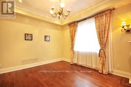 A room with a chandelier, two picture frames on the wall, and a window with curtains.