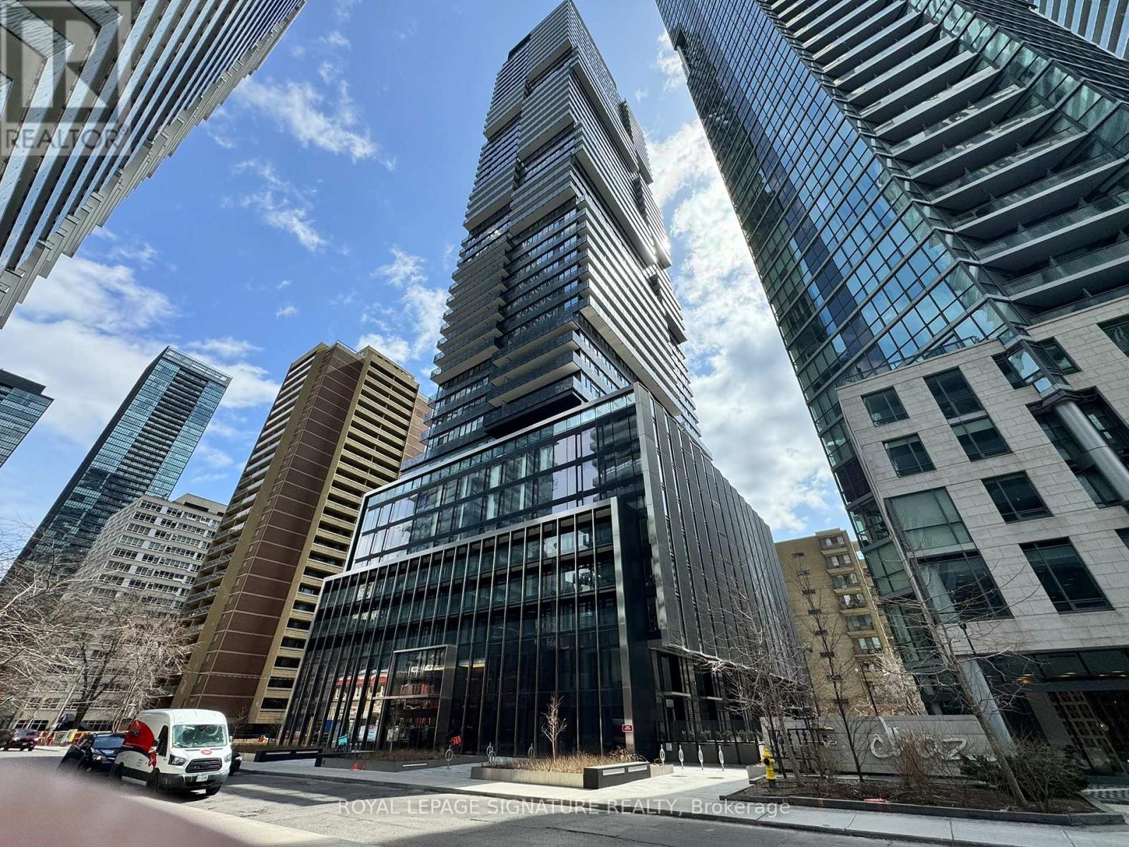 A tall building with a curved glass facade stands in front of other buildings.