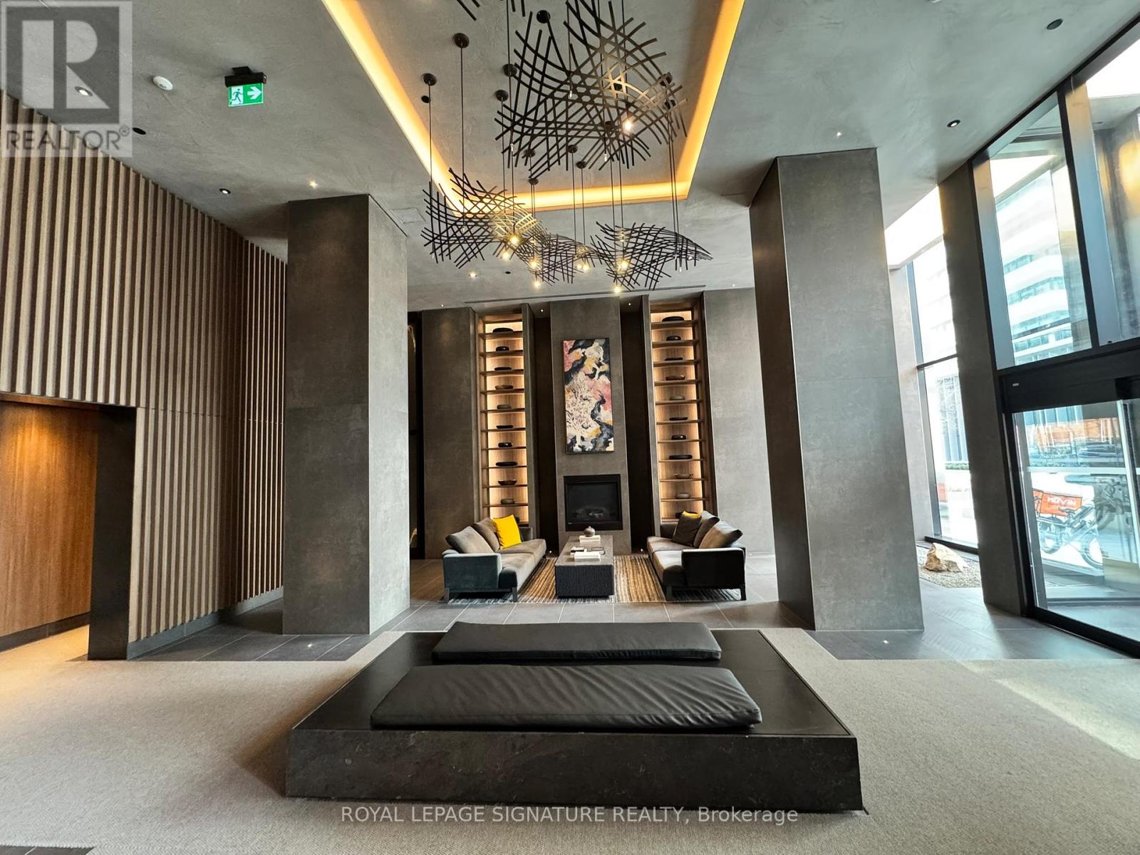 A modern living room with a large black sofa and a chandelier.