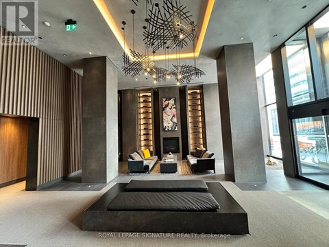 A modern living room with a large black sofa and a chandelier.