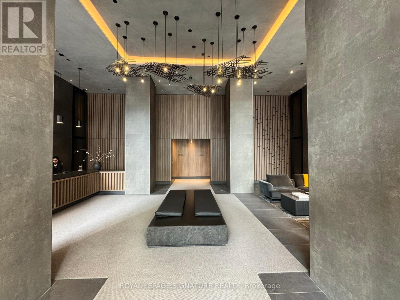 A spacious lobby with a large marble table and a chandelier hanging from the ceiling.