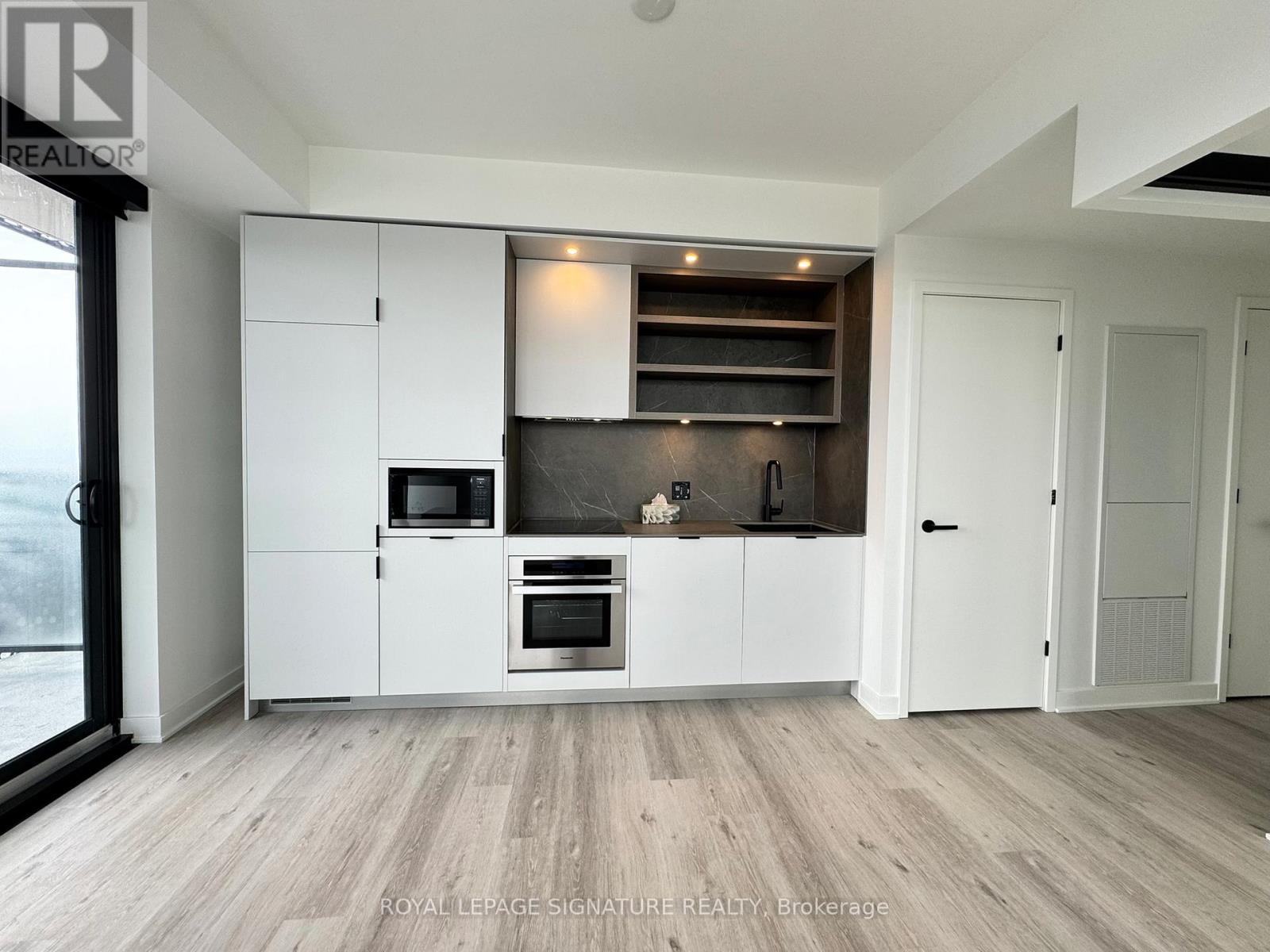 A modern kitchen with white cabinets and a wooden floor.