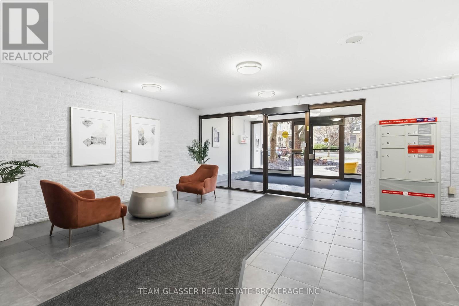 A real estate brokerage office with a white brick wall and a glass door.