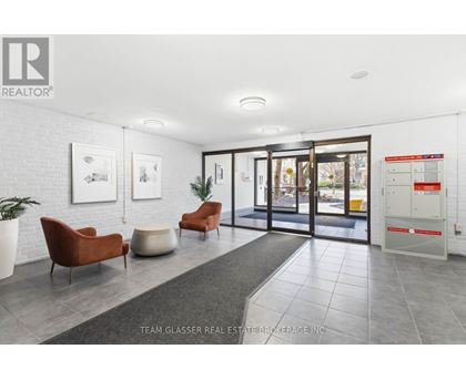 A real estate brokerage office with a white brick wall and a glass door.