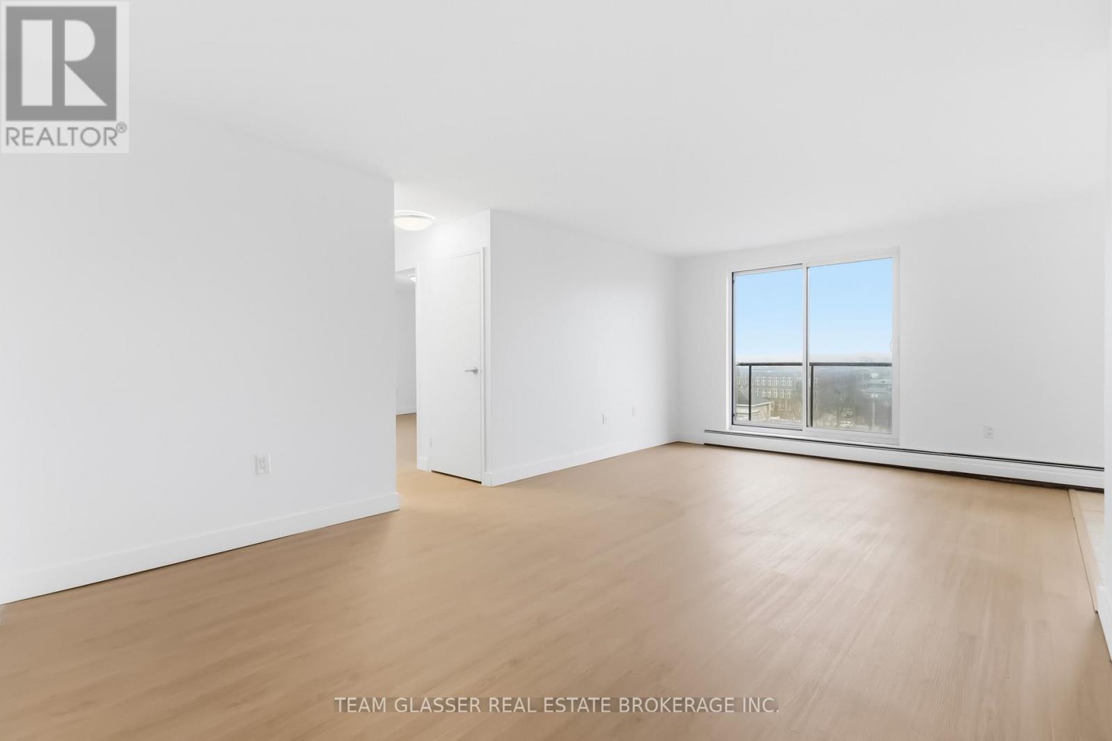 A white room with a window and wooden flooring.