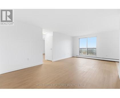 A white room with a window and wooden flooring.